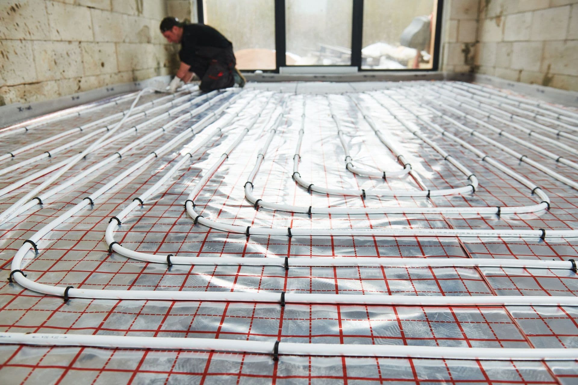 Underfloor heating pipes being laid on a grid
